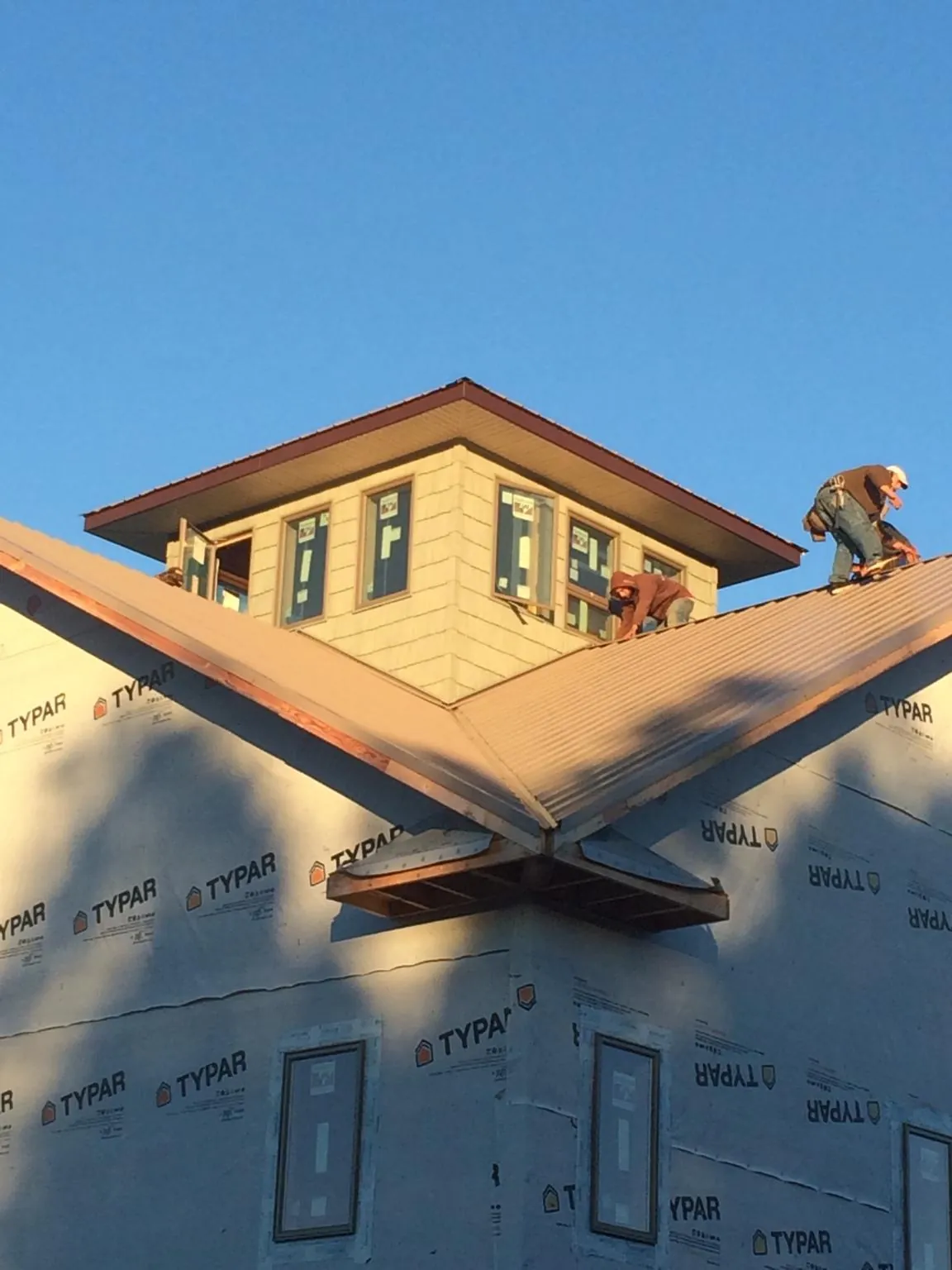 Roofers working around a rooftop cupola on a new metal roof at sunset — Roof Waterproofing in Lexington by Roofing Brothers